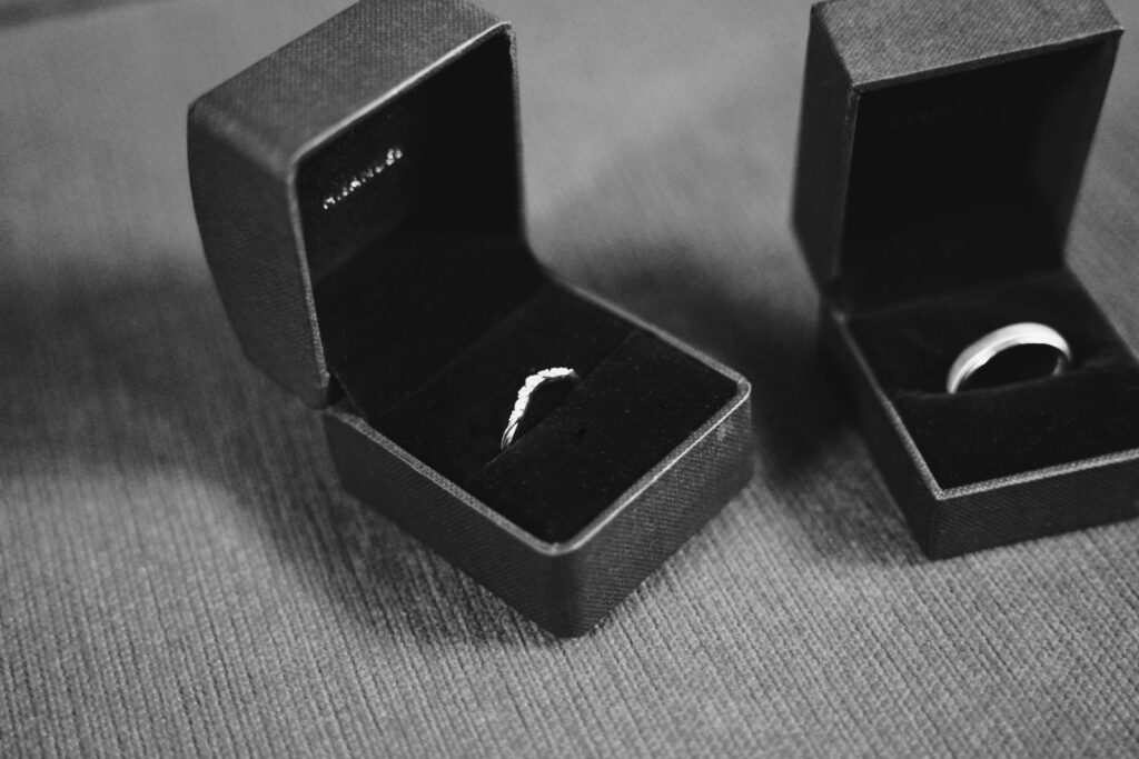 A black-and-white close-up of a wedding band and an engagement ring in open jewelry boxes, evoking the long customer relationship a retention program is built to sustain